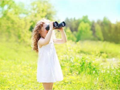 girl in white dress in field with binoculars birdwatching - Get Kids Interested In Birdwatching
